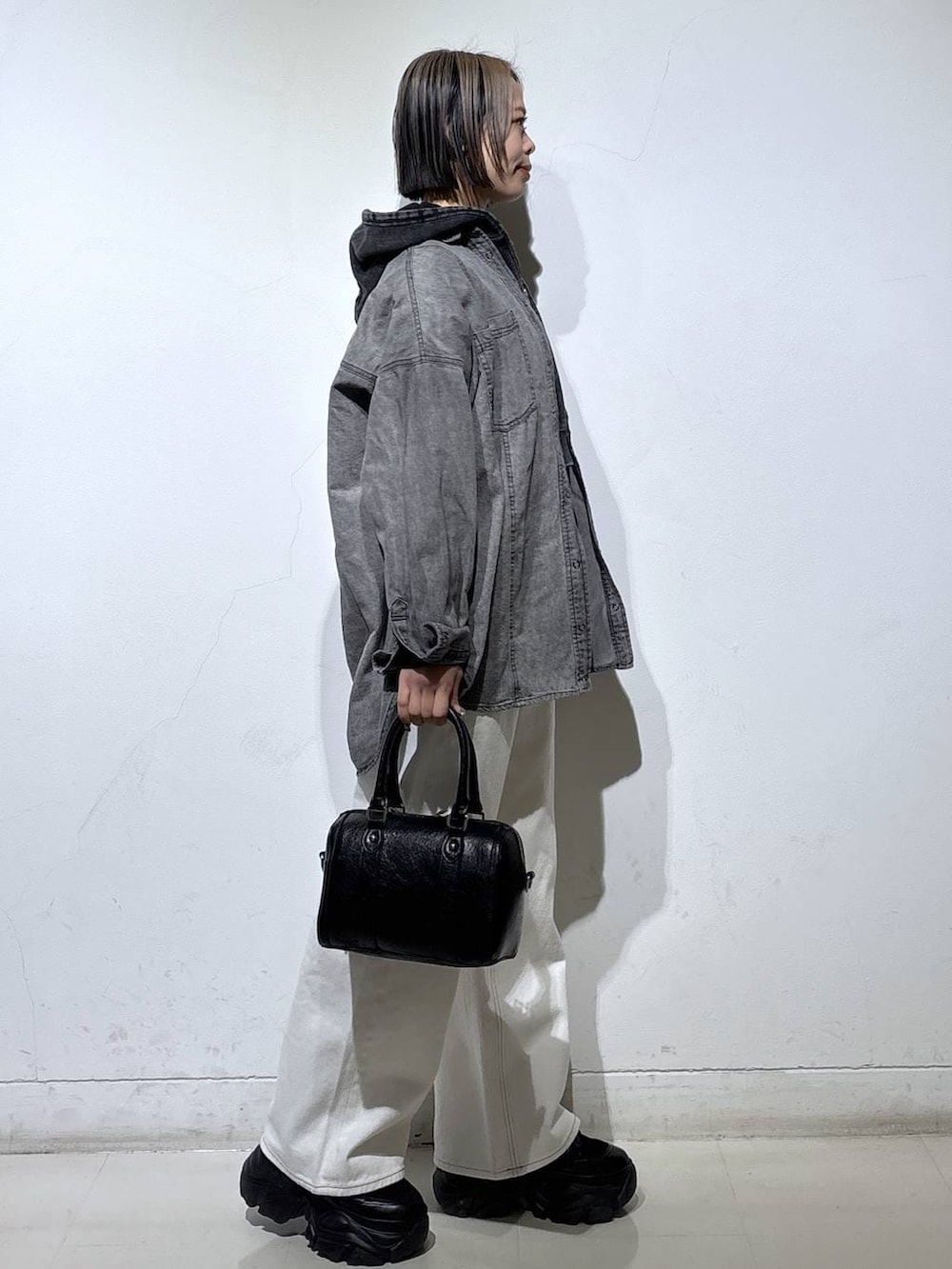 ブラック系のブーツ、ブラック系のTシャツ/カットソー、ホワイト系のスラックスを着用したレディースの冬コーディネートの3枚目の写真