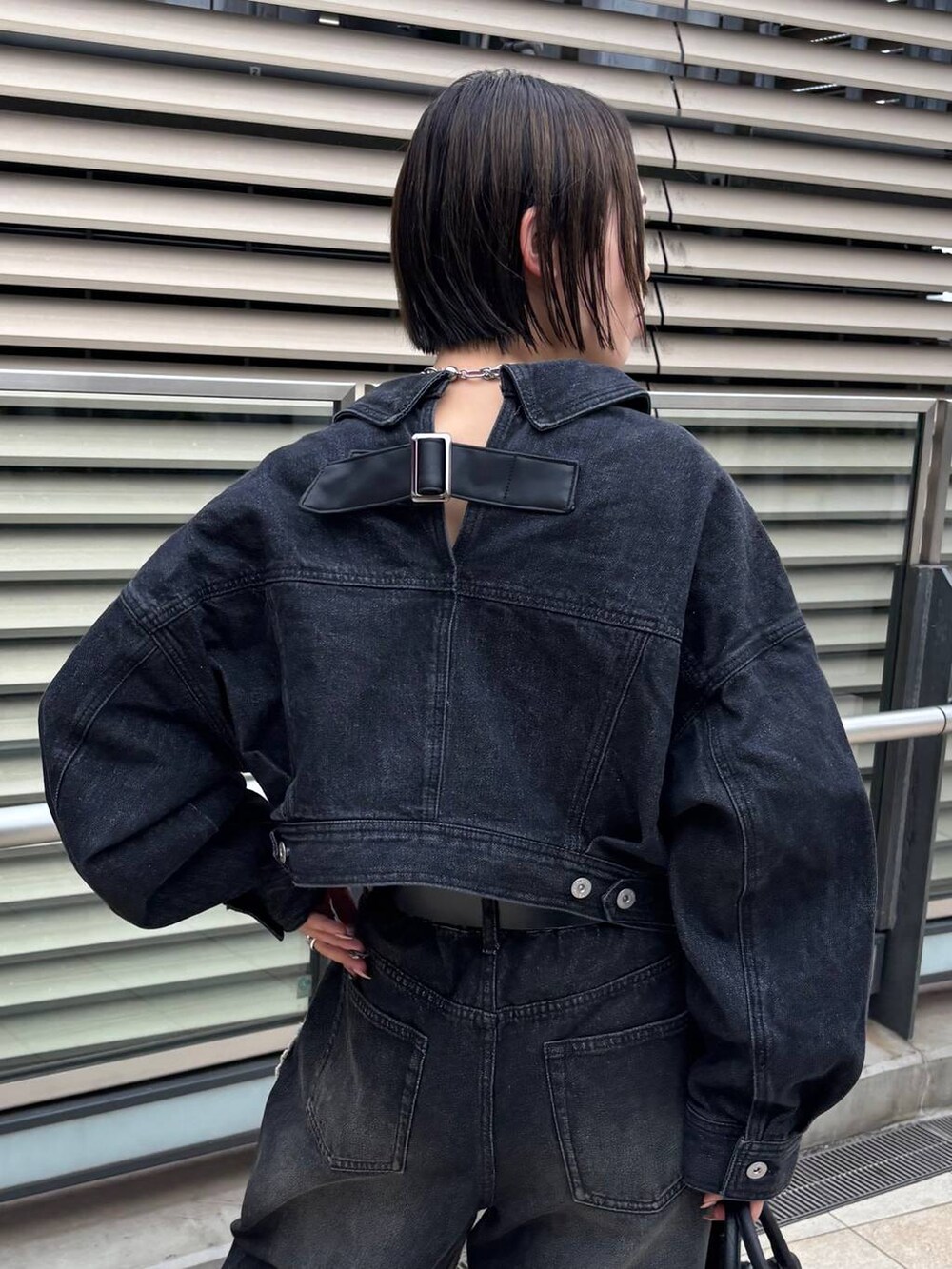 ブラック系のショルダーバッグ、ブラック系のデニムジャケット、ブラック系のデニムパンツを着用したレディースの秋コーディネートの7枚目の写真
