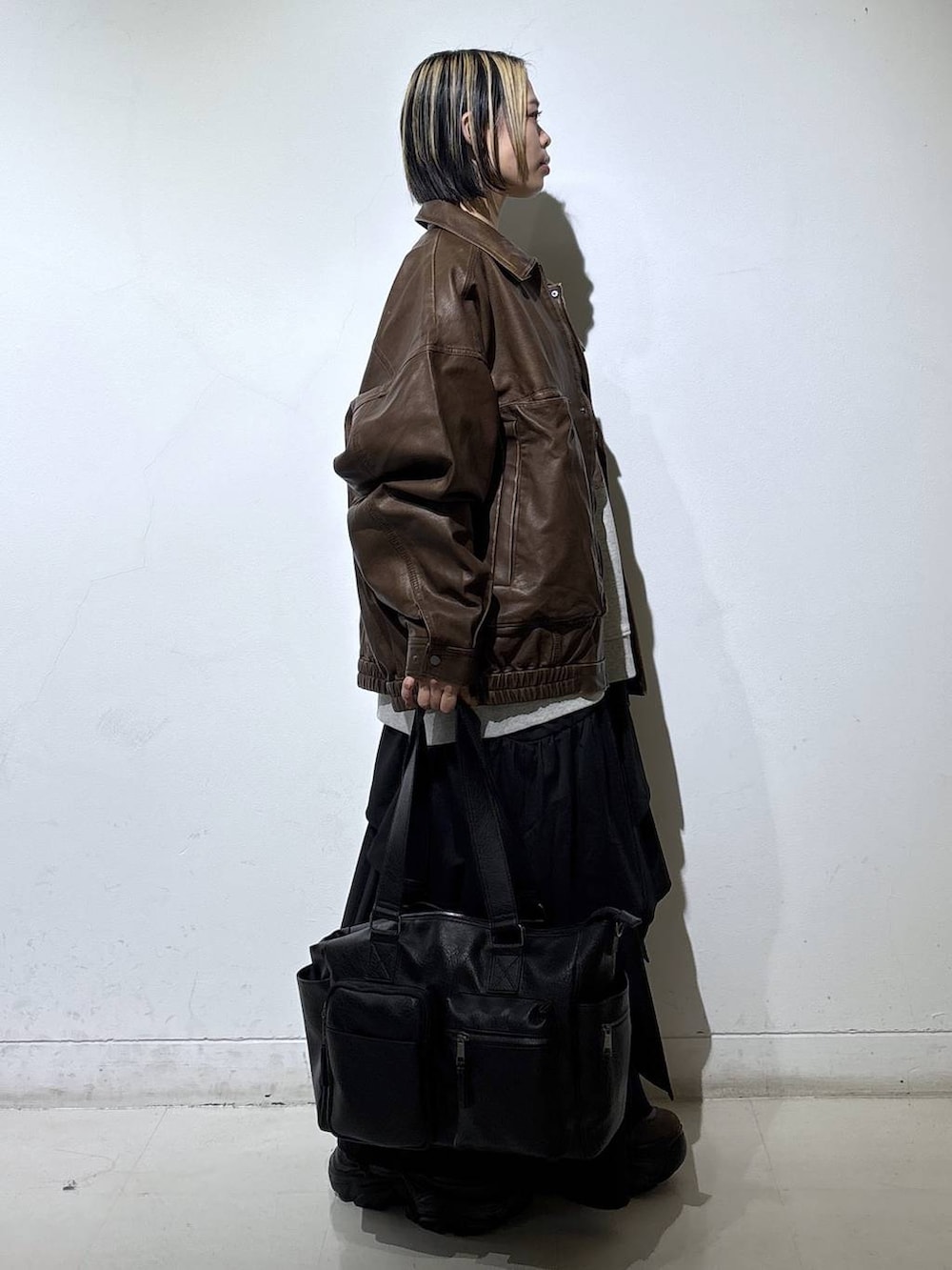 ブラウン系のブーツ、ブラック系のボストンバッグ、ブラック系のスカートを着用したレディースの冬コーディネートの3枚目の写真