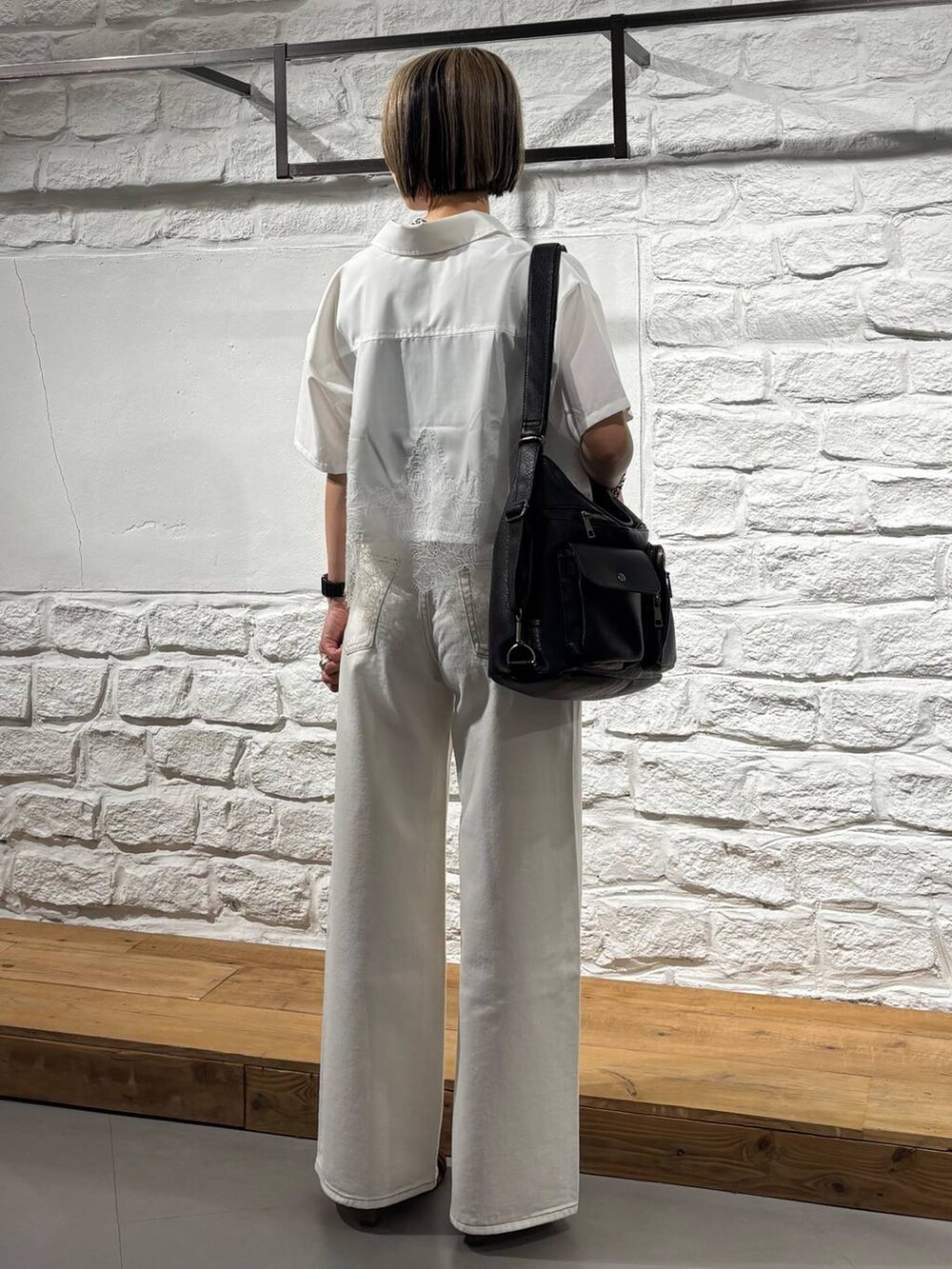 ブラック系のデニムパンツ、ブラック系のショルダーバッグ、イエロー系のサンダルを着用したレディースの春コーディネートの5枚目の写真