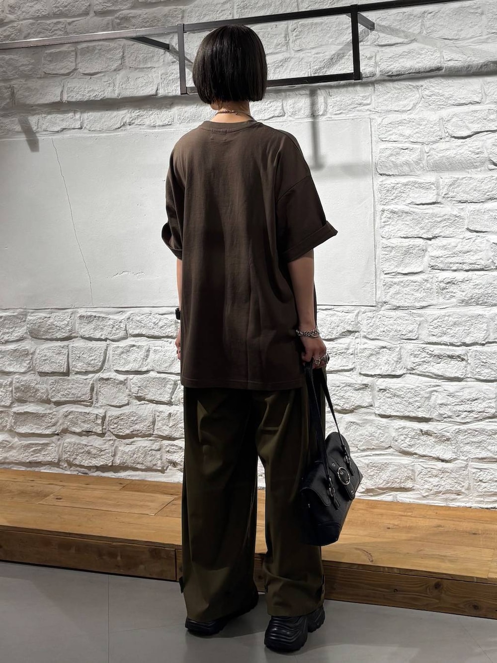 グリーン系のスラックス、ブラウン系のTシャツ/カットソー、ブラック系のサンダルを着用したレディースの夏コーディネートの6枚目の写真