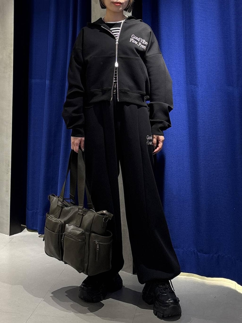 ブラック系のスニーカー、グリーン系のボストンバッグ、ブラック系のパーカーを着用したレディースの冬コーディネートの3枚目の写真