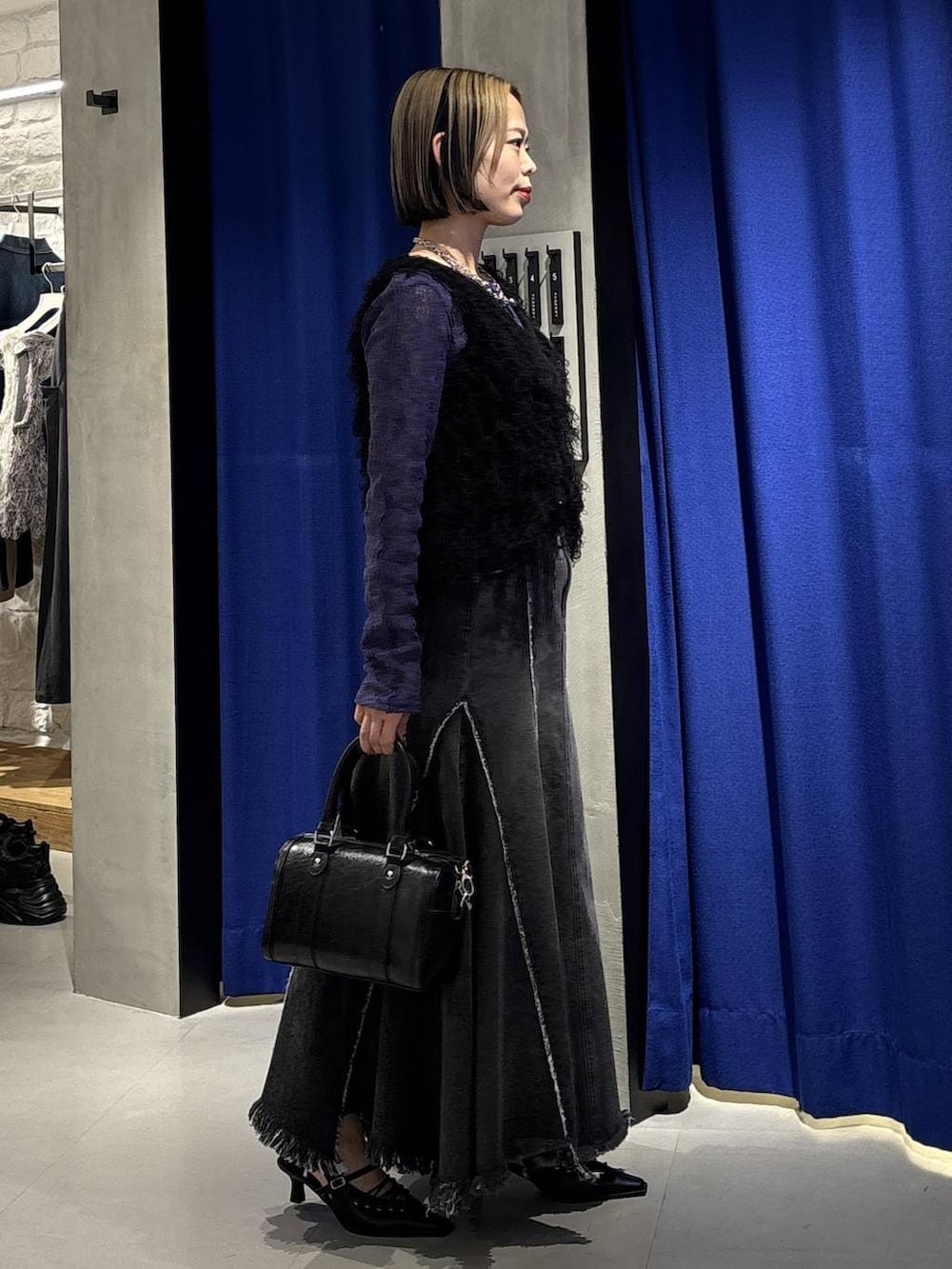 ブラック系のボストンバッグ、ブラック系のサンダル、ブラック系のデニムスカートを着用したレディースの冬コーディネートの4枚目の写真