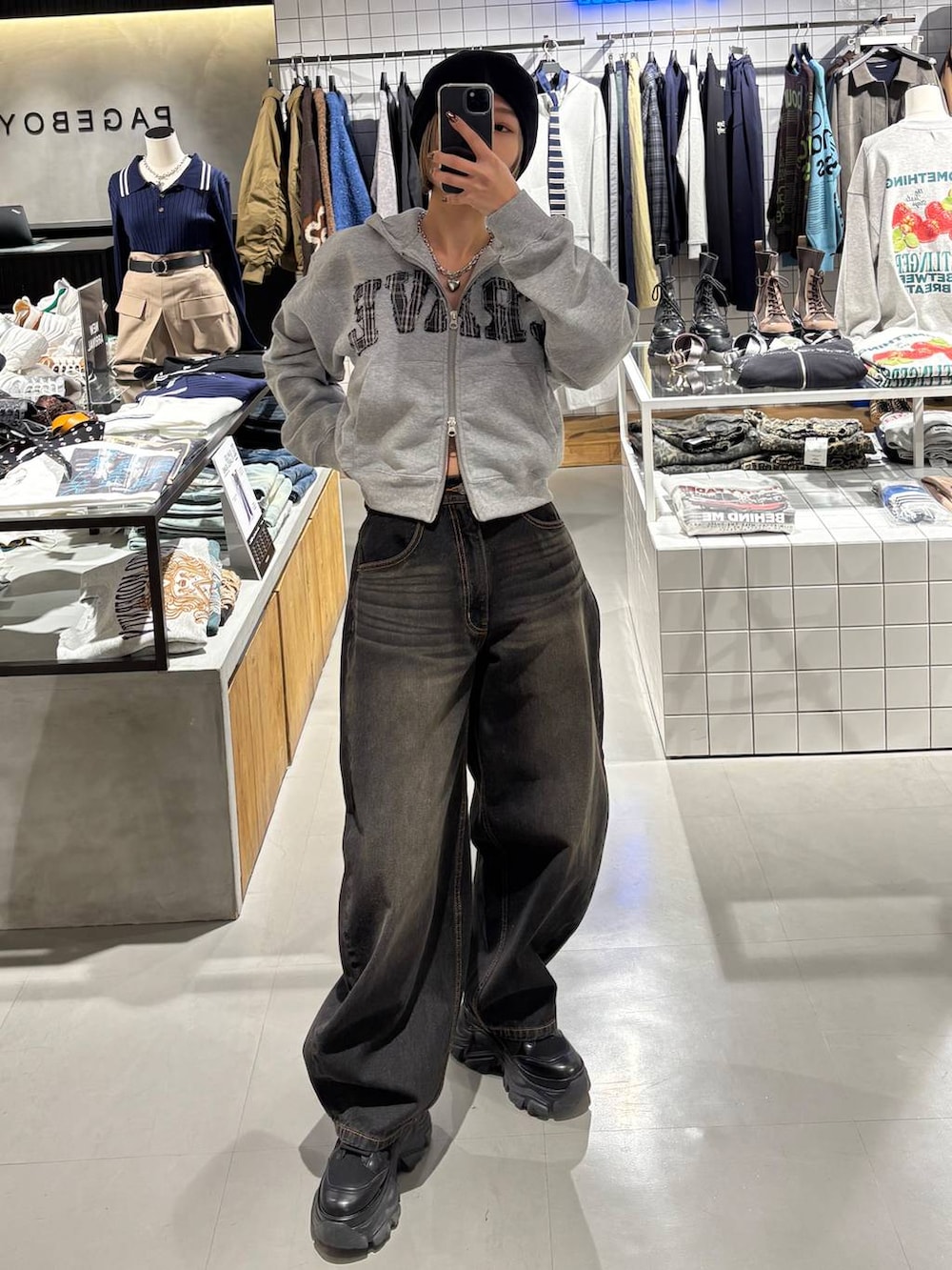 ブラック系のブーツ、ブラック系のデニムパンツ、グレー系のパーカーを着用したレディースの冬コーディネートの2枚目の写真