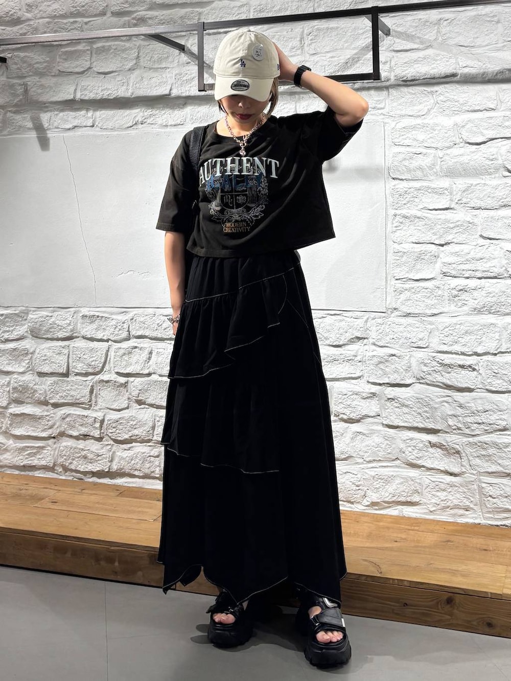 ブラック系のスカート、グレー系のTシャツ/カットソー、ブラック系のショルダーバッグを着用したレディースの夏コーディネートの2枚目の写真