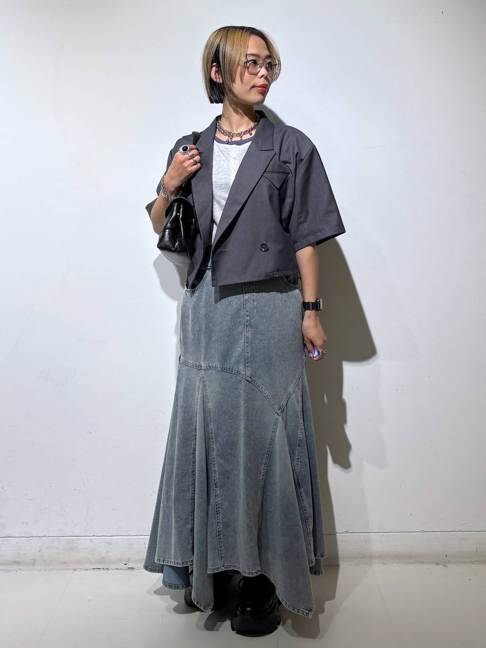 ブラック系のスニーカー、ブルー系のデニムスカート、グレー系のTシャツ/カットソーを着用したレディースの夏コーディネートの2枚目の写真