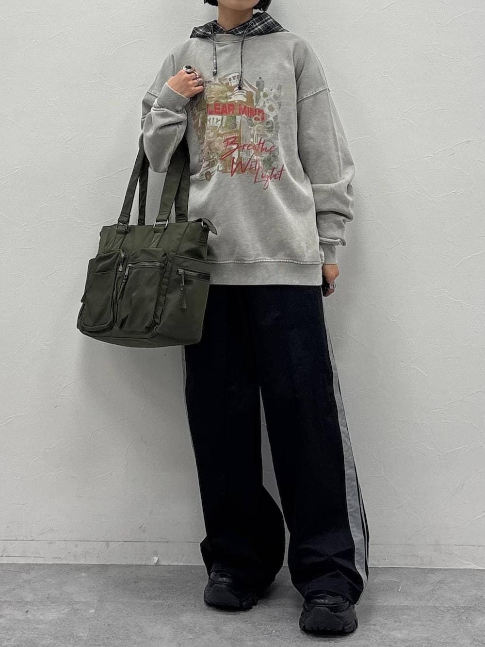 ブラック系のスニーカー、グリーン系のボストンバッグ、ブラック系のスウェットパンツを着用したレディースの冬コーディネートの2枚目の写真