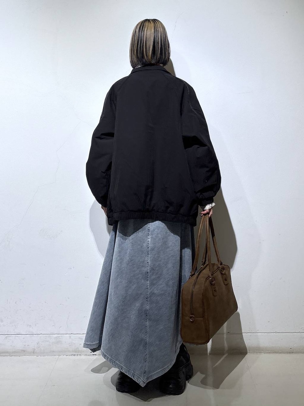 ブラック系のブーツ、ベージュ系のボストンバッグ、ブラック系のナイロンジャケットを着用したレディースの春コーディネートの4枚目の写真