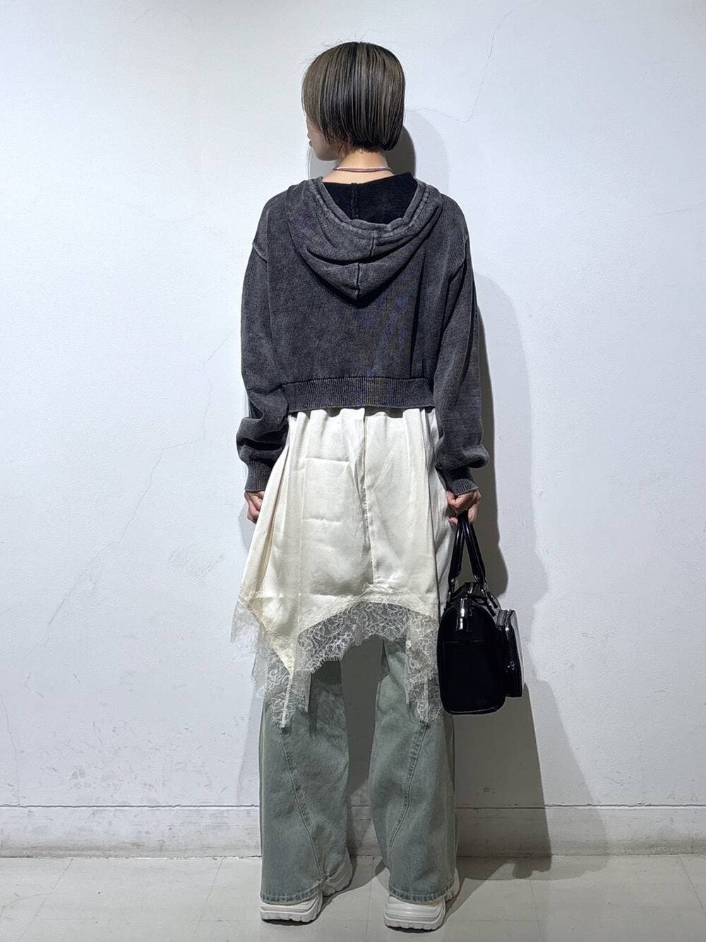 ホワイト系のスニーカー、ブルー系のデニムパンツ、ブラック系のショルダーバッグを着用したレディースの春コーディネートの4枚目の写真