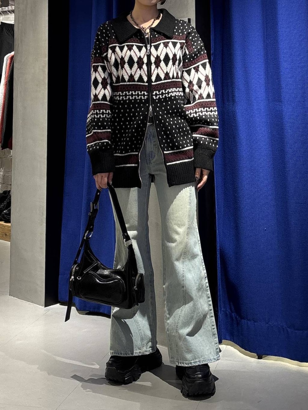 ブラック系のブーツ、ブルー系のデニムパンツ、ブラック系のショルダーバッグを着用したレディースの冬コーディネートの2枚目の写真