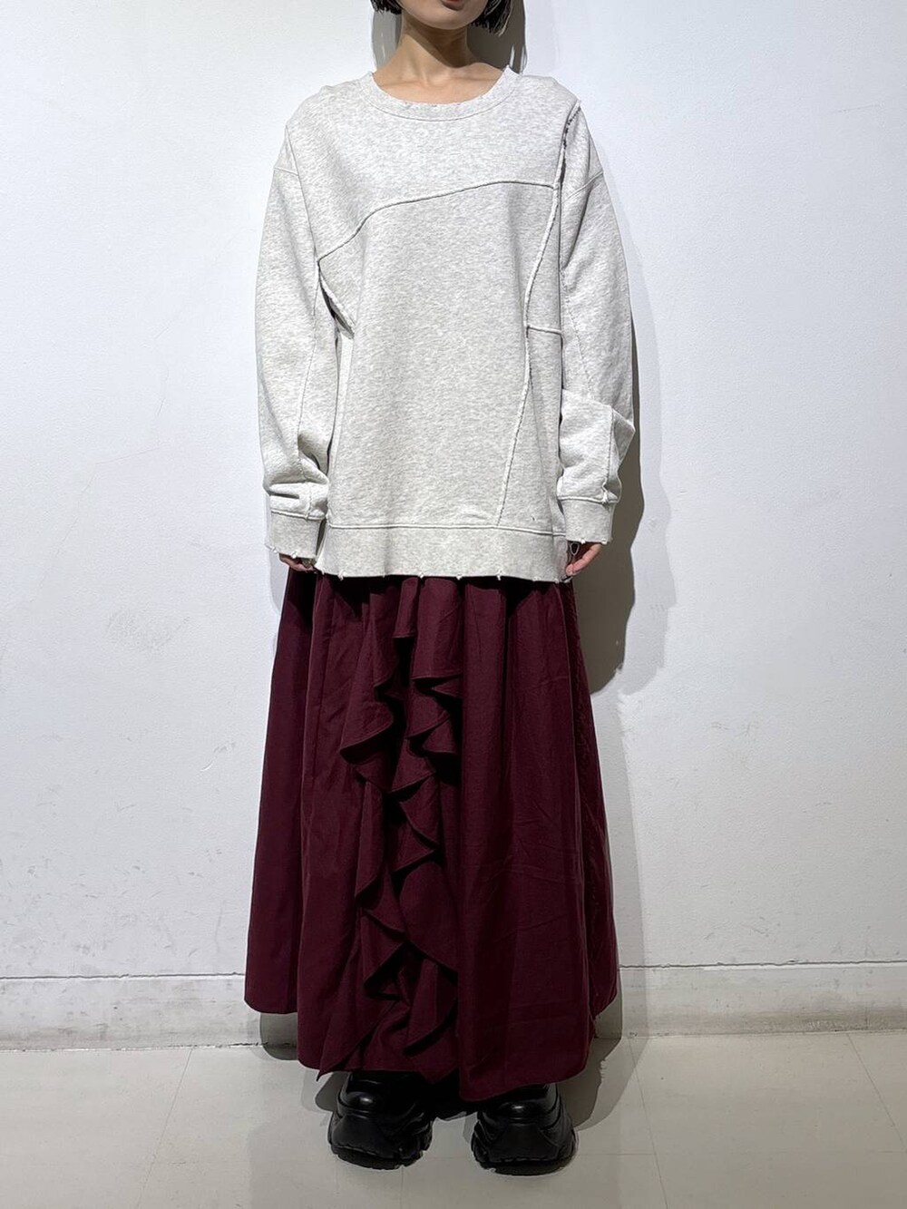 ブラック系のブーツ、ベージュ系のスウェット、レッド系のスカートを着用したレディースの秋コーディネートの2枚目の写真