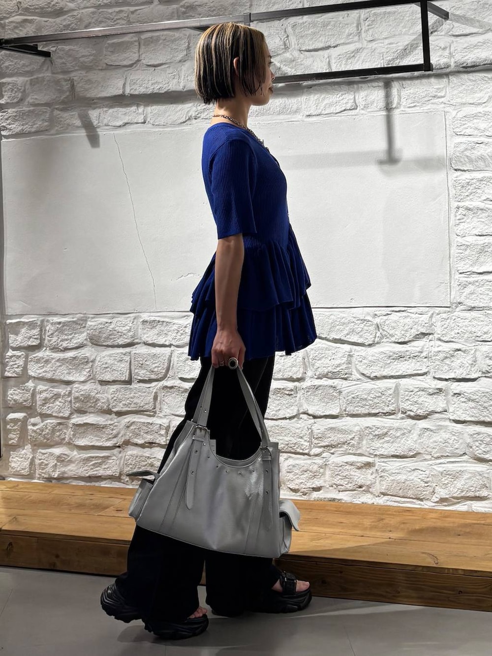 ブラック系のデニムパンツ、グレー系のサンダル、シルバー系のハンドバッグを着用したレディースの春コーディネートの4枚目の写真
