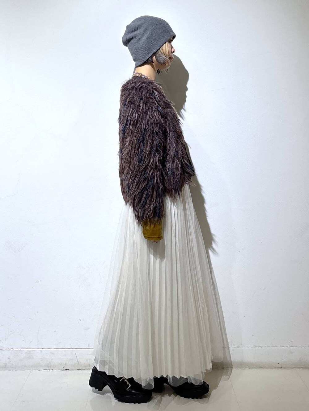 ブラック系のブーツ、ホワイト系のスカート、ブラウン系のカーディガン/ボレロを着用したレディースの冬コーディネートの3枚目の写真