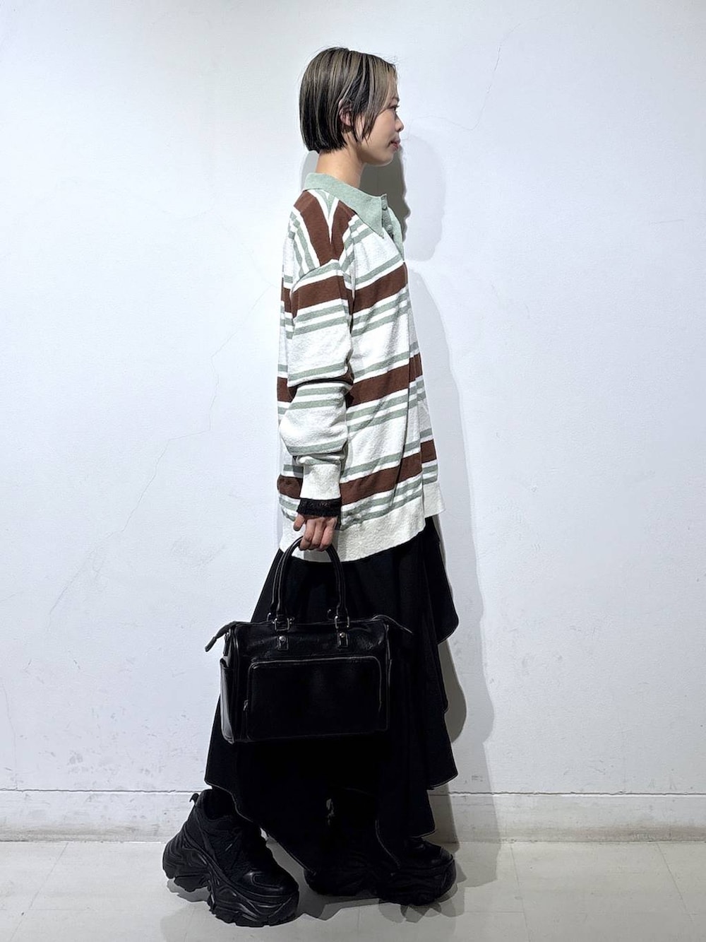 ブラック系のスニーカー、ブラック系のスカート、ブラック系のショルダーバッグを着用したレディースの春コーディネートの3枚目の写真