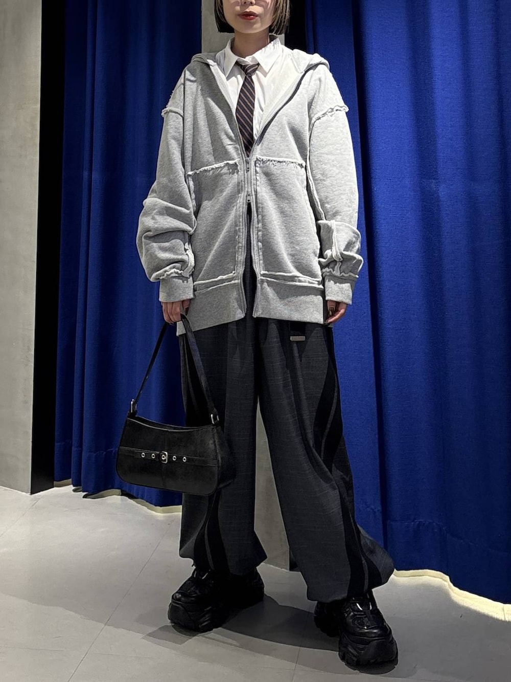 ブラック系のスニーカー、ブラック系のハンドバッグ、グレー系のその他パンツを着用したレディースの冬コーディネートの2枚目の写真