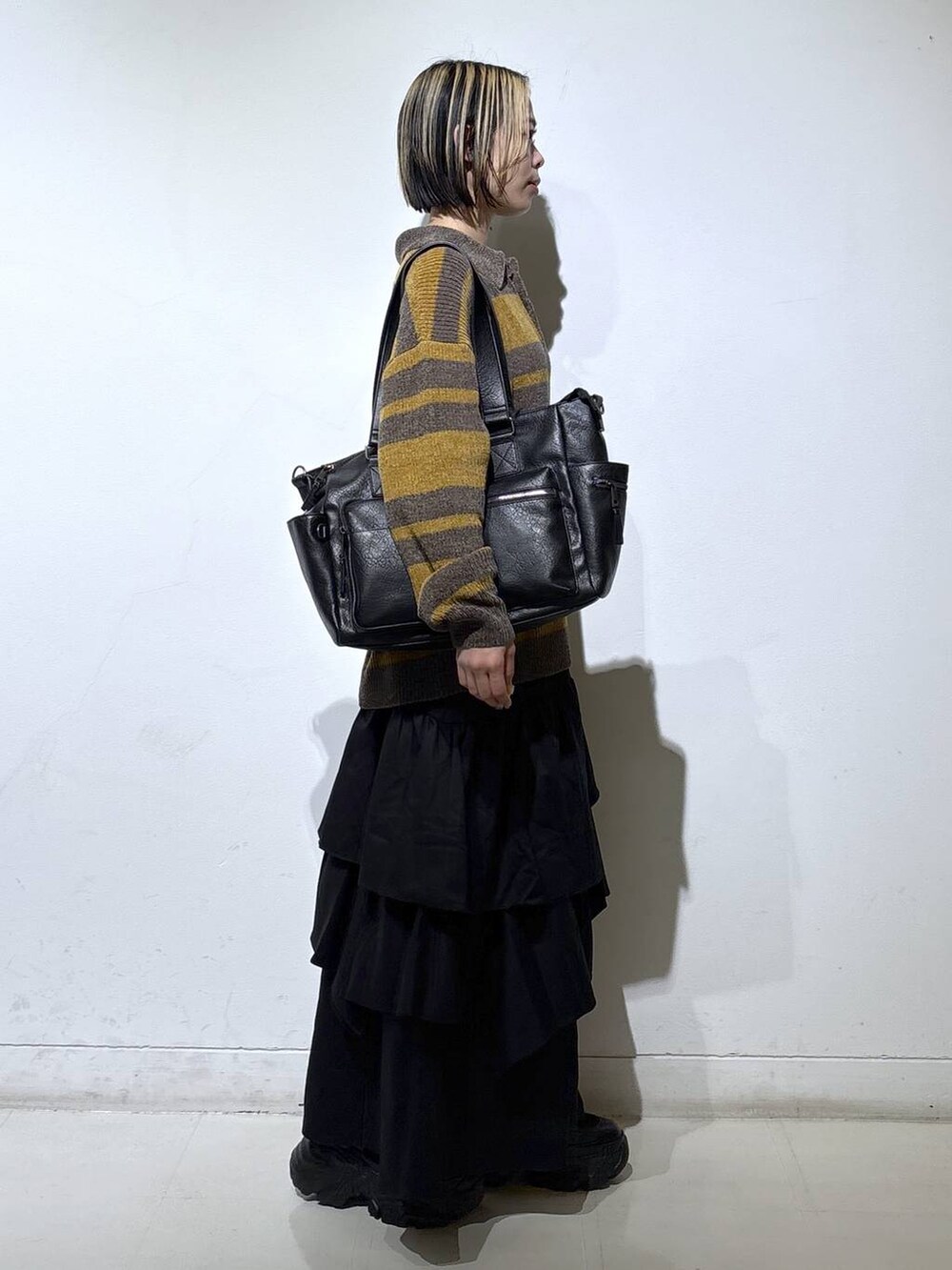 ブラック系のブーツ、ブラック系のボストンバッグ、ブラック系のスカートを着用したレディースの秋コーディネートの3枚目の写真