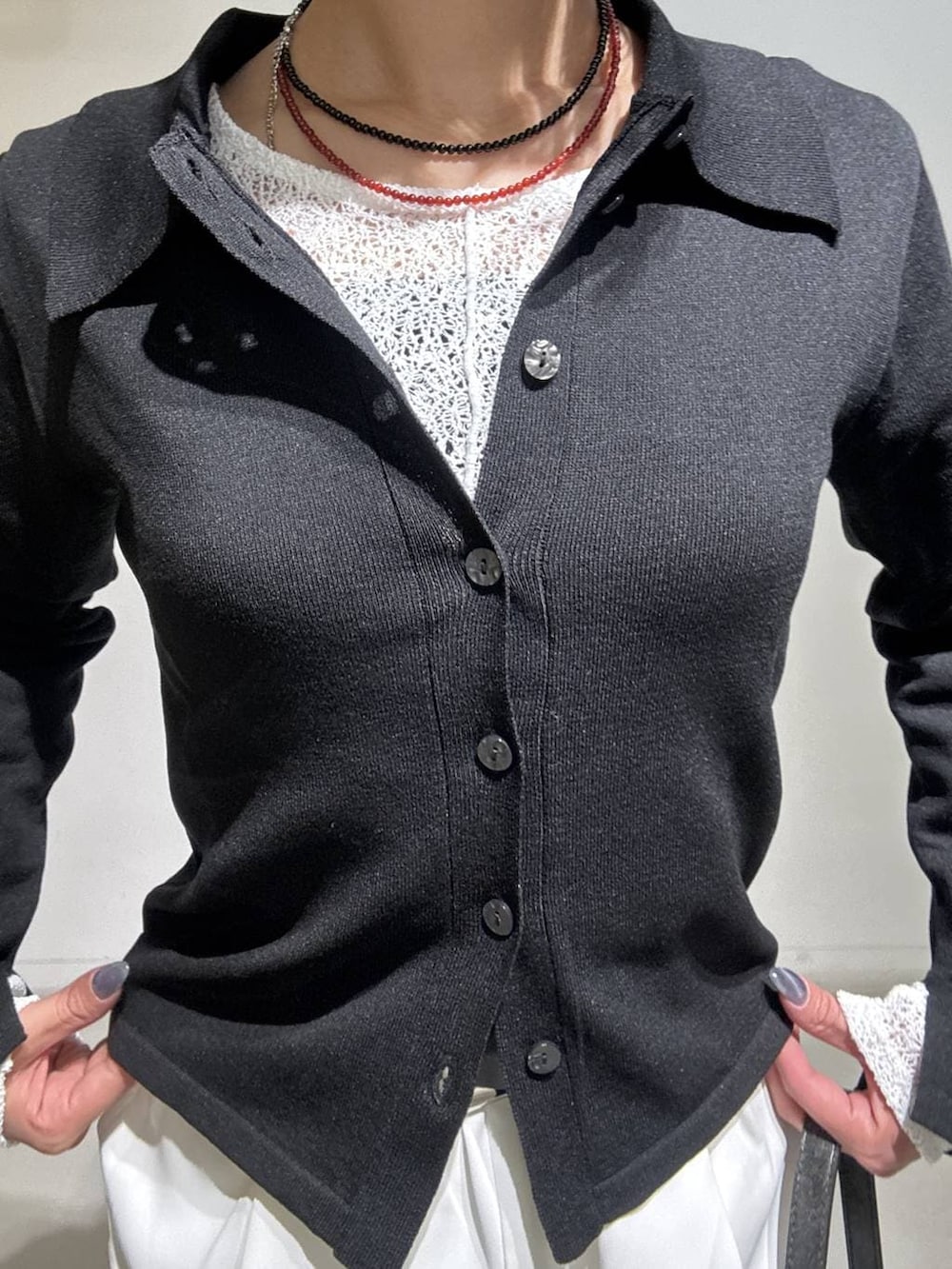 ブラック系のハンドバッグ、ブラウン系のサンダル、ホワイト系のスラックスを着用したレディースの冬コーディネートの5枚目の写真