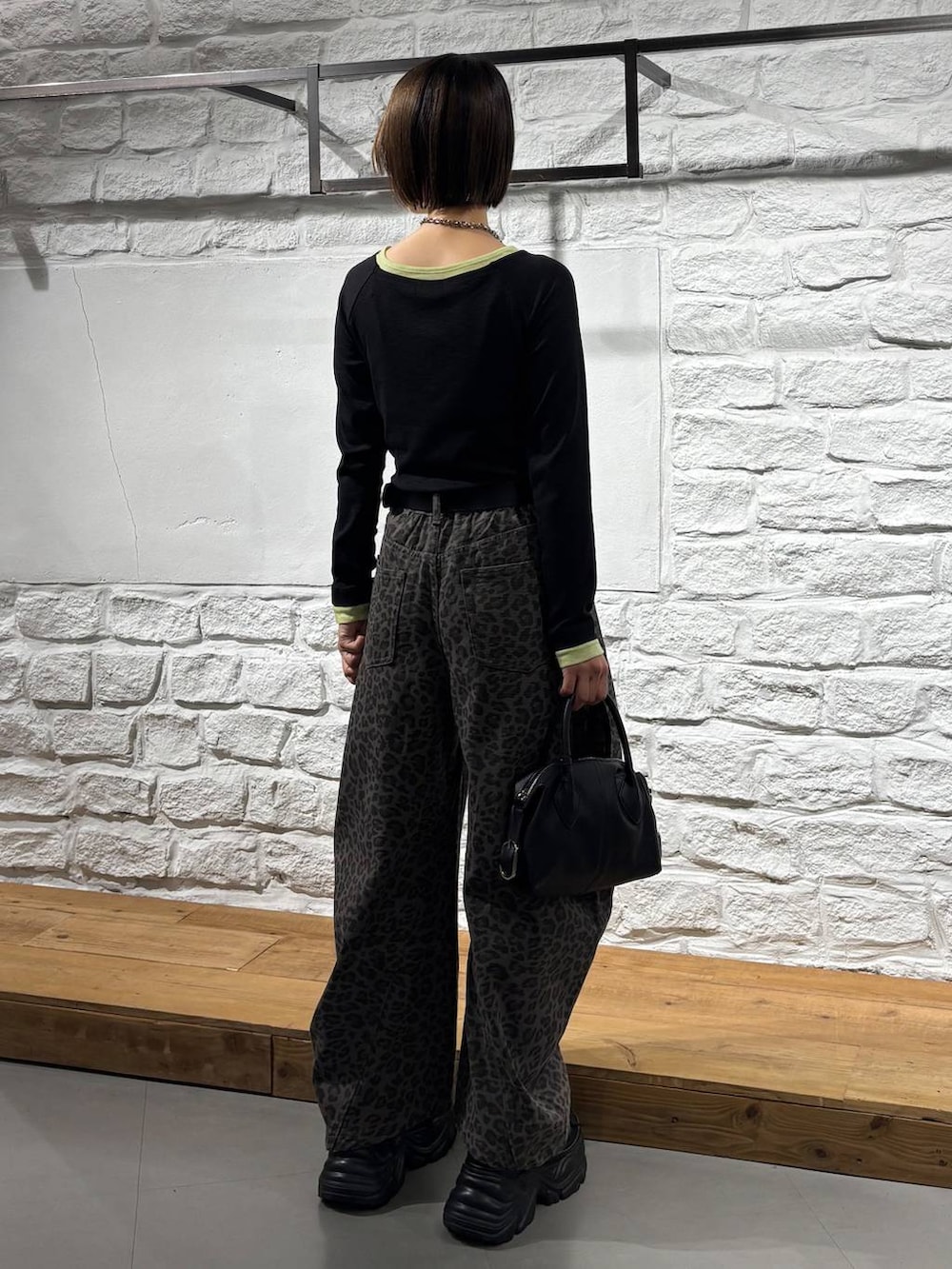 ブラック系のTシャツ/カットソー、ブラック系のスニーカー、ブラック系のショルダーバッグを着用したレディースの秋コーディネートの6枚目の写真