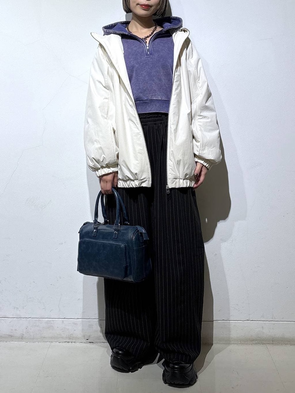 ブラック系のブーツ、ホワイト系のナイロンジャケット、ブルー系のパーカーを着用したレディースの冬コーディネートの2枚目の写真