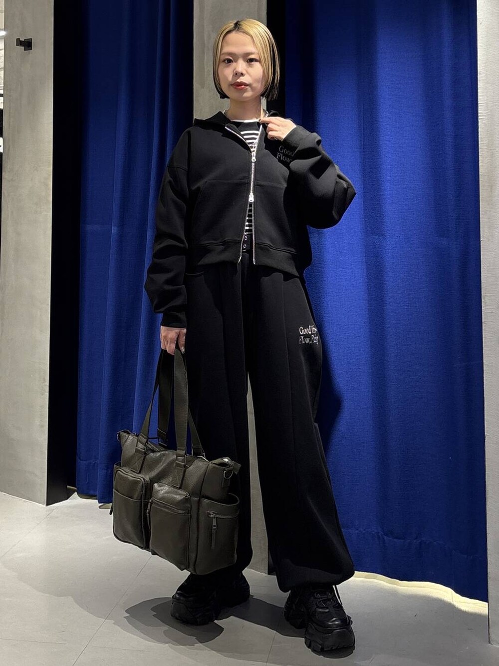 ブラック系のスニーカー、グリーン系のボストンバッグ、ブラック系のパーカーを着用したレディースの冬コーディネートの2枚目の写真