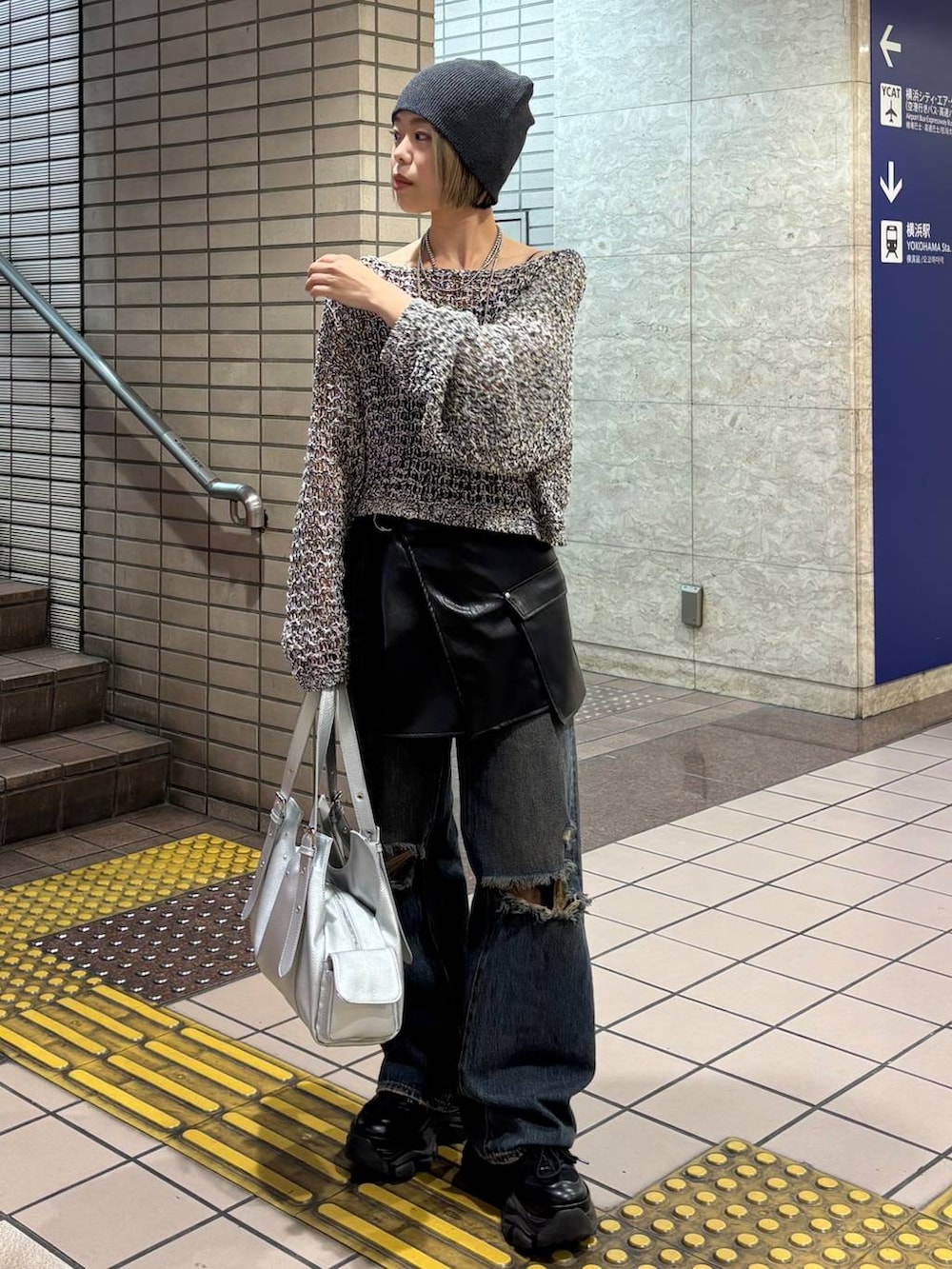 ブラック系のスニーカー、ブラック系のニット/セーター、シルバー系のハンドバッグを着用したレディースの春コーディネートの4枚目の写真