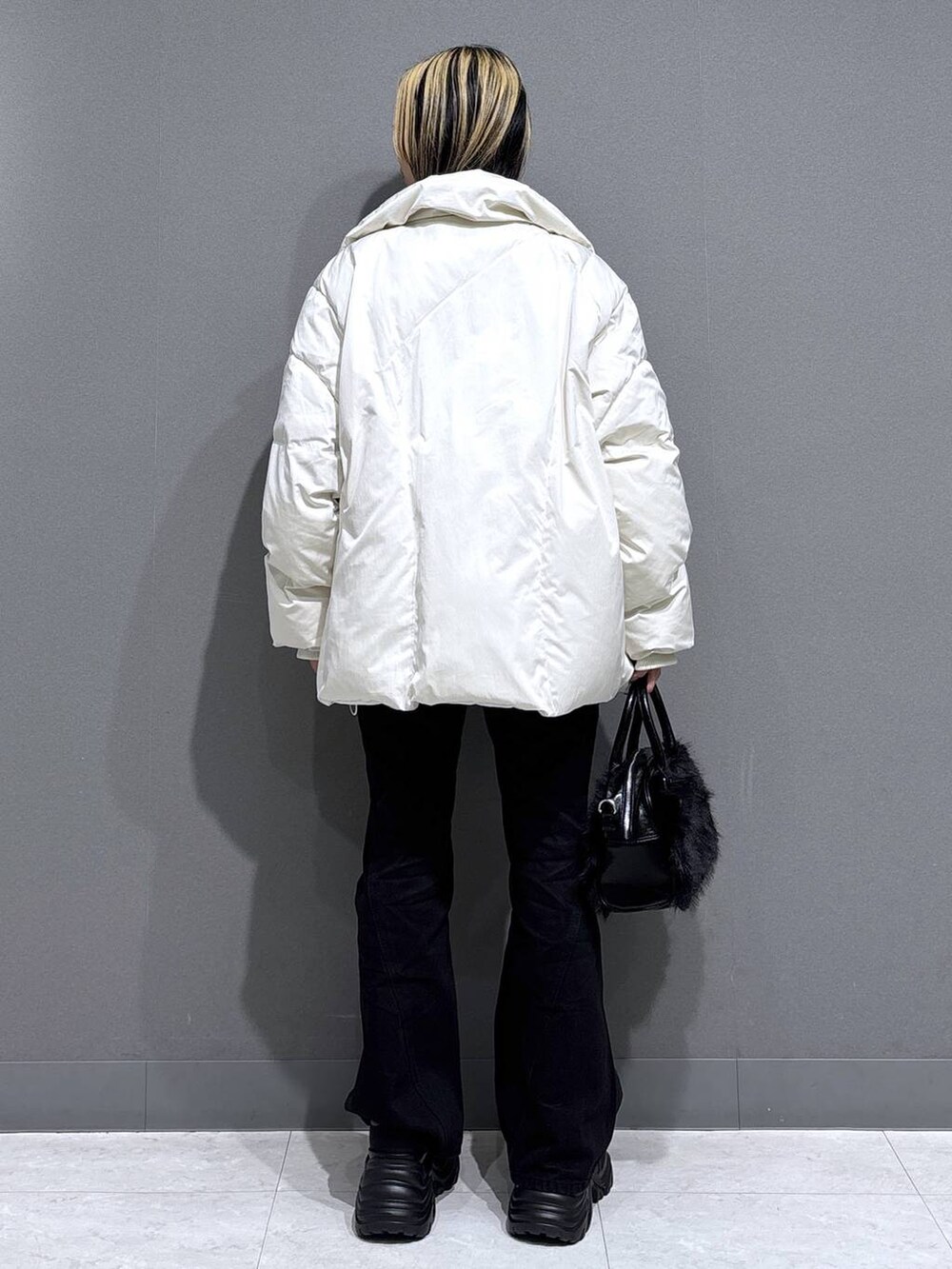 ブラック系のブーツ、ブラック系のデニムパンツ、ホワイト系のブルゾンを着用したレディースの冬コーディネートの4枚目の写真