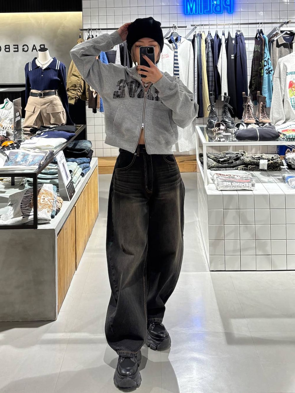 ブラック系のブーツ、ブラック系のデニムパンツ、グレー系のパーカーを着用したレディースの冬コーディネートの4枚目の写真