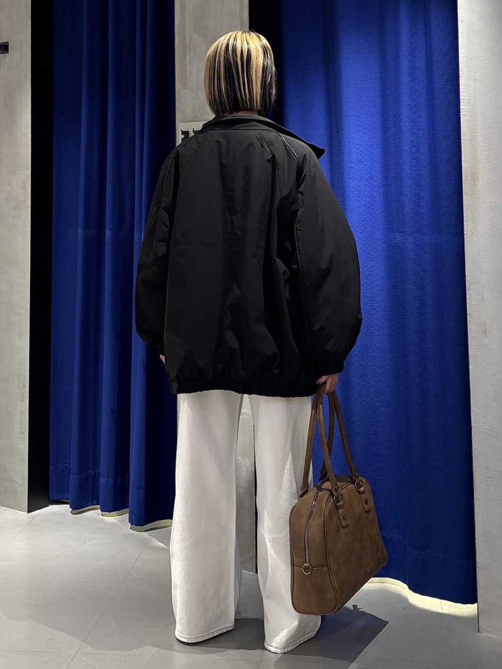 ベージュ系のボストンバッグ、ホワイト系のスラックス、ブラック系のナイロンジャケットを着用したレディースの冬コーディネートの5枚目の写真