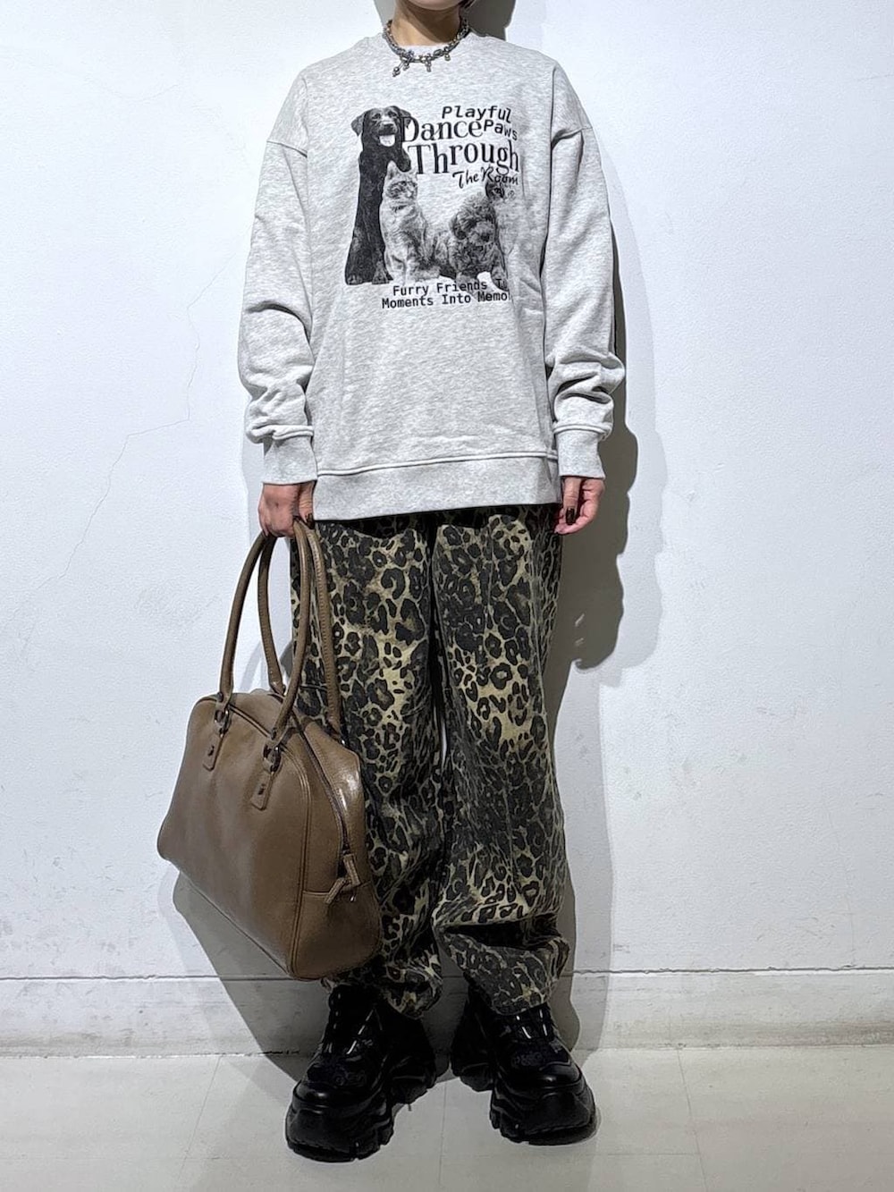 ブラック系のブーツ、ベージュ系のボストンバッグ、グレー系のスウェットを着用したレディースの冬コーディネートの2枚目の写真