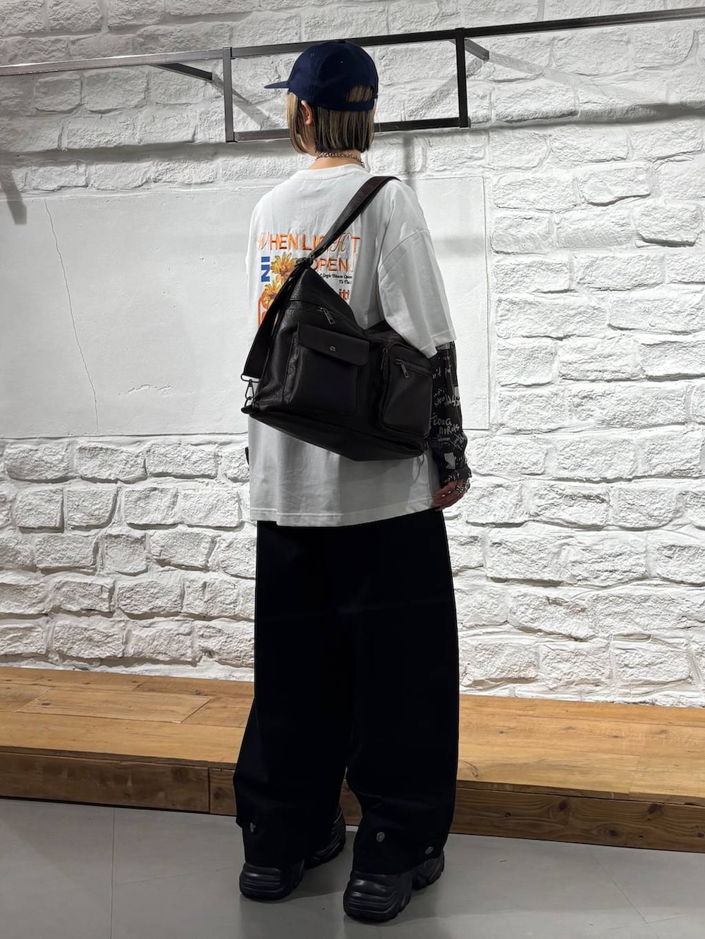 ブラック系のスラックス、ブラック系のスニーカー、ブラウン系のショルダーバッグを着用したレディースの夏コーディネートの6枚目の写真