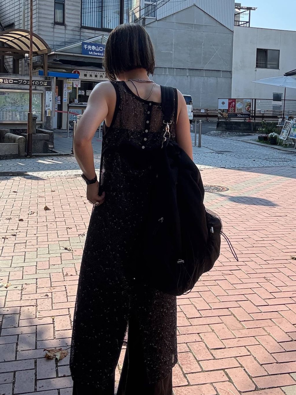 ブラウン系のデニムパンツ、ブラック系のサンダル、ブラック系のワンピースを着用したレディースの夏コーディネートの5枚目の写真