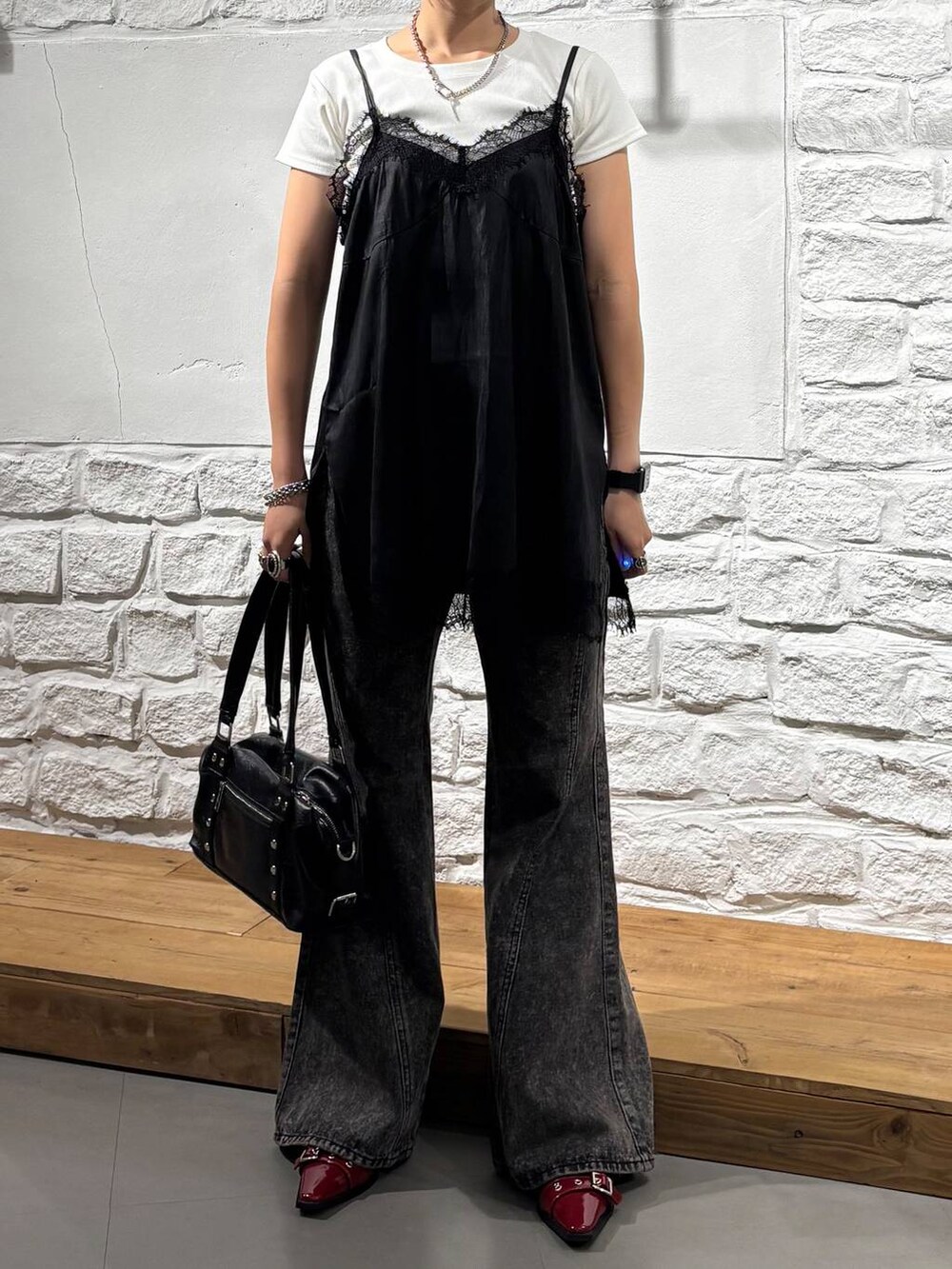 ブラック系のキャミソール、ブラック系のショルダーバッグ、ブラック系のデニムパンツを着用したレディースの秋コーディネートの3枚目の写真