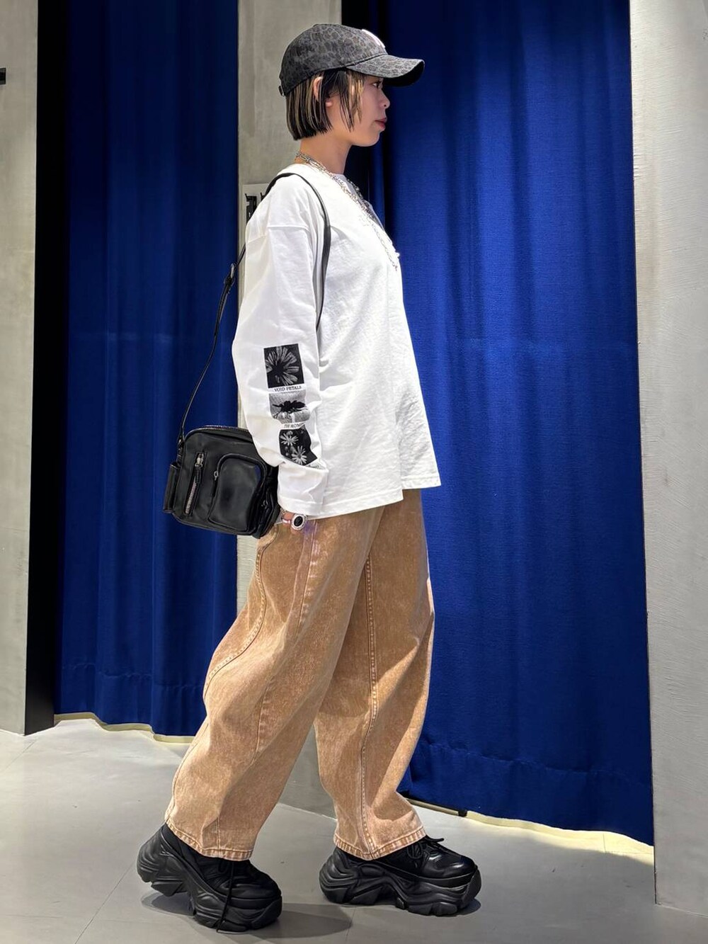 ブラック系のスニーカー、ブラウン系のデニムパンツ、ブラック系のショルダーバッグを着用したレディースの春コーディネートの4枚目の写真