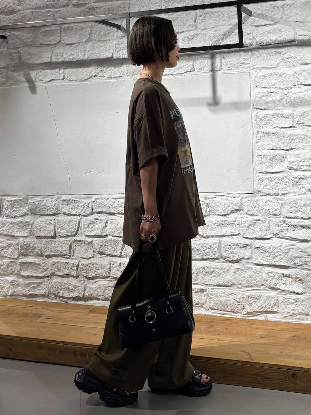 グリーン系のスラックス、ブラウン系のTシャツ/カットソー、ブラック系のサンダルを着用したレディースの夏コーディネートの5枚目の写真