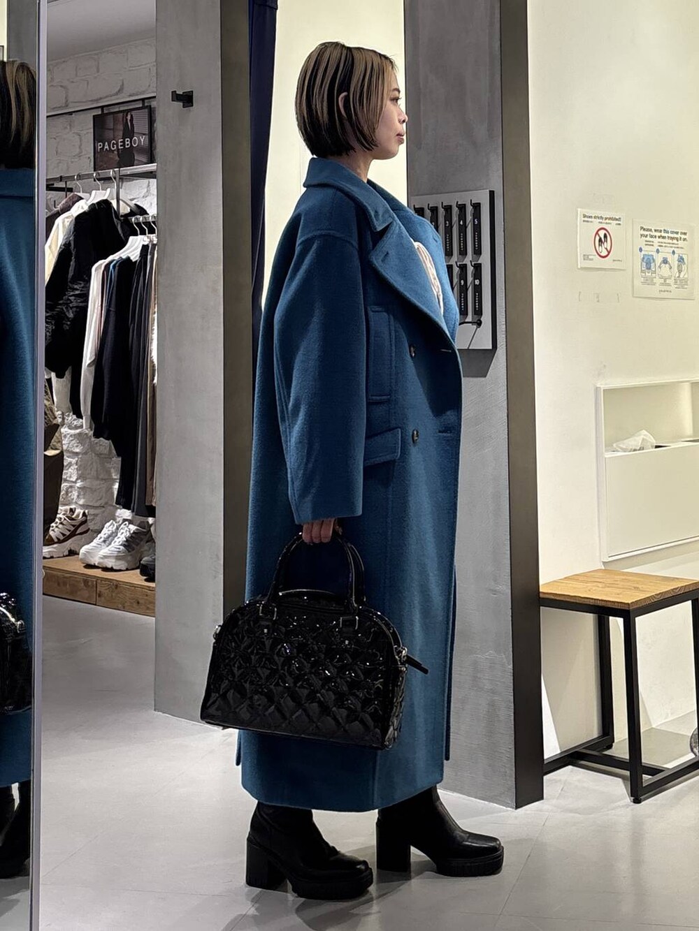 グリーン系のチェスターコート、ブラック系のブーツ、ブラック系のその他パンツを着用したレディースの冬コーディネートの3枚目の写真