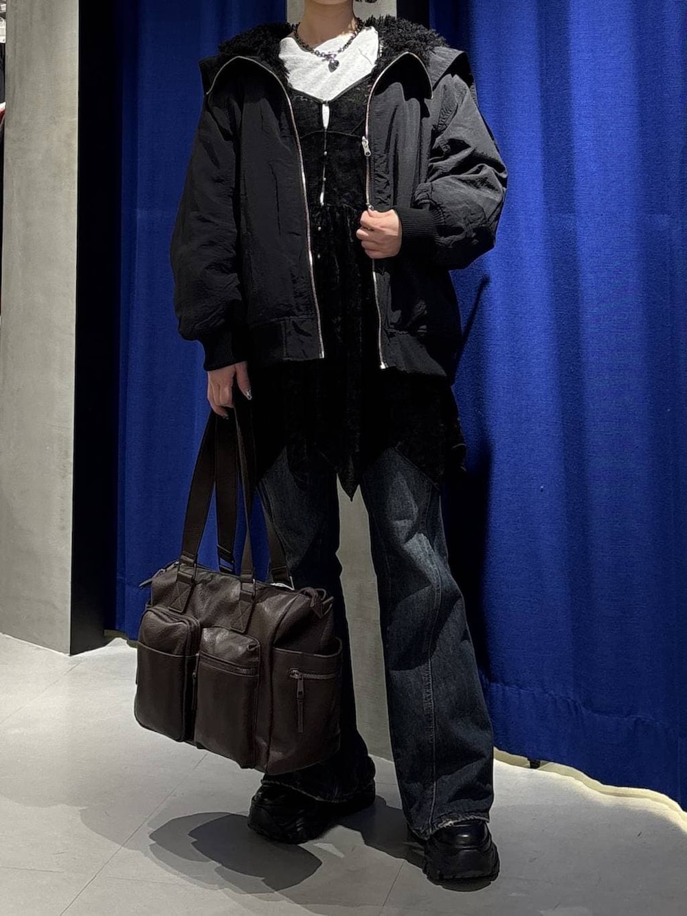 ブラック系のスニーカー、ブルー系のデニムパンツ、ブラウン系のボストンバッグを着用したレディースの冬コーディネートの2枚目の写真