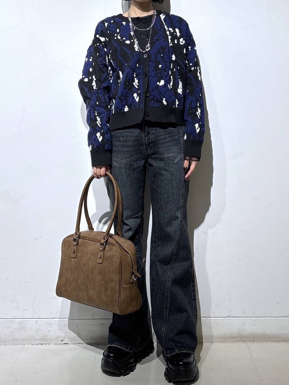 ブラック系のスニーカー、ベージュ系のボストンバッグ、ブルー系のデニムパンツを着用したレディースの冬コーディネートの2枚目の写真