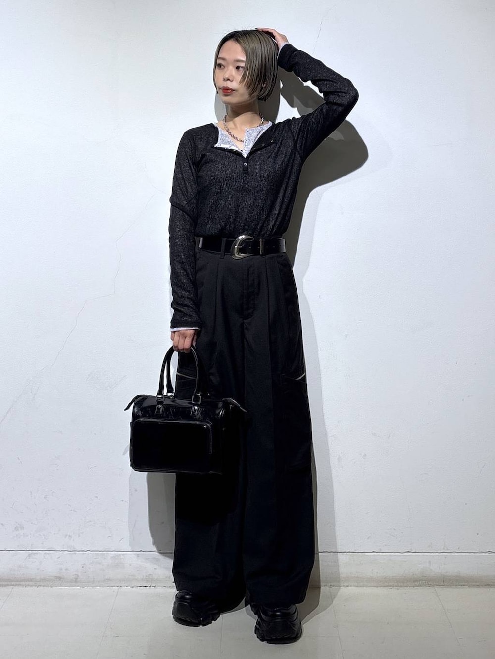 ブラック系のスニーカー、ブラック系のショルダーバッグ、ブラック系のスラックスを着用したレディースの冬コーディネートの3枚目の写真