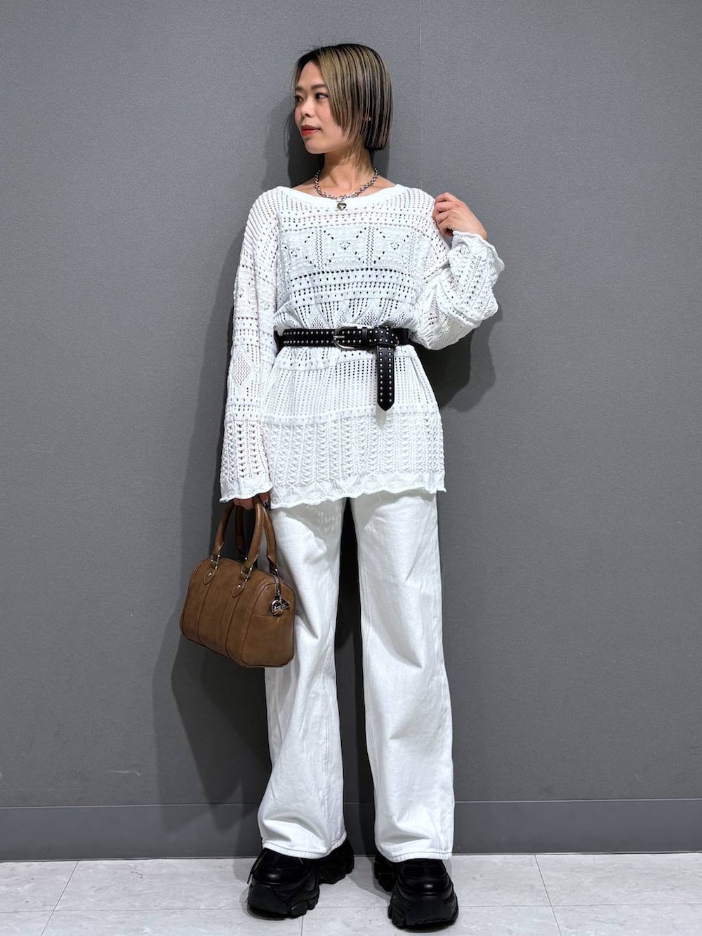 ブラック系のスニーカー、ホワイト系のスラックス、ブラウン系のボストンバッグを着用したレディースの春コーディネートの2枚目の写真