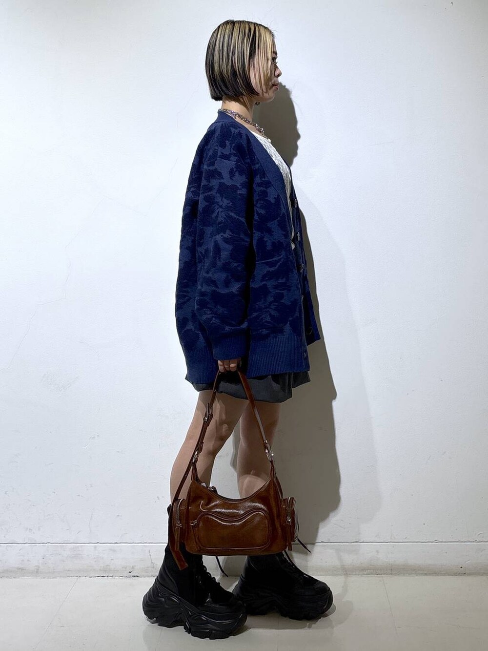 ブラック系のブーツ、ホワイト系のTシャツ/カットソー、ブラウン系のショルダーバッグを着用したレディースの秋コーディネートの3枚目の写真