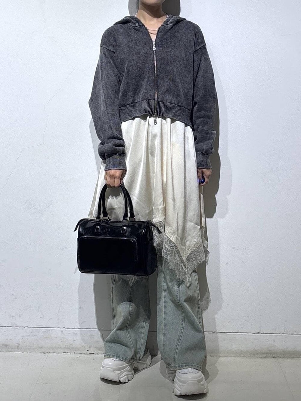 ホワイト系のスニーカー、ブルー系のデニムパンツ、ブラック系のショルダーバッグを着用したレディースの春コーディネートの2枚目の写真