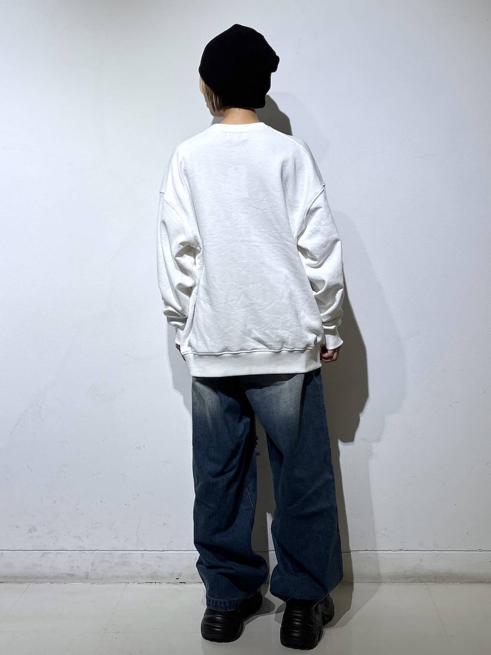 ブラック系のブーツ、ブルー系のデニムパンツ、ホワイト系のスウェットを着用したレディースの秋コーディネートの4枚目の写真