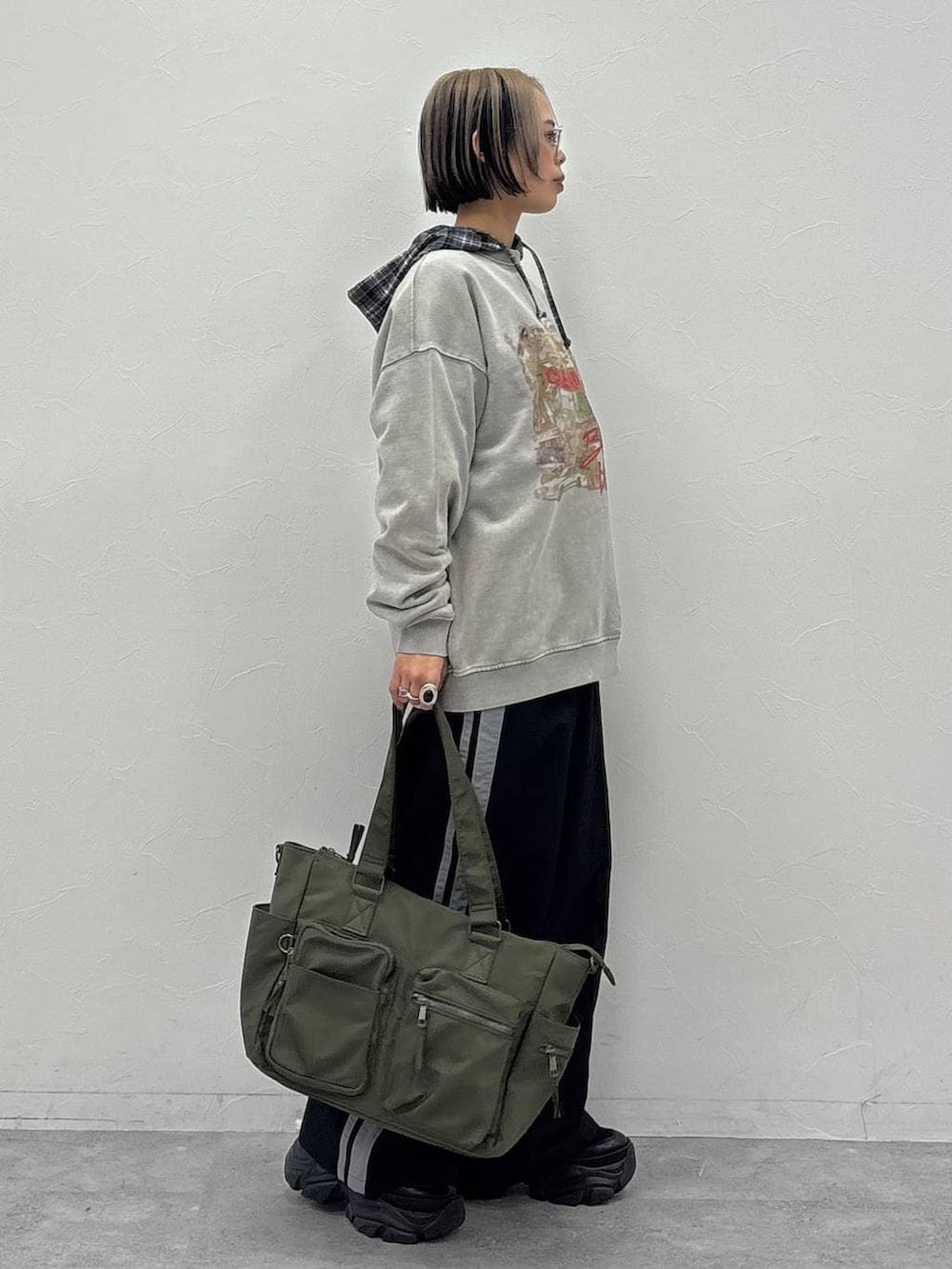 ブラック系のスニーカー、グリーン系のボストンバッグ、ブラック系のスウェットパンツを着用したレディースの冬コーディネートの3枚目の写真