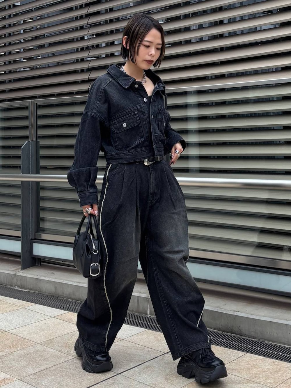 ブラック系のショルダーバッグ、ブラック系のデニムジャケット、ブラック系のデニムパンツを着用したレディースの秋コーディネートの3枚目の写真