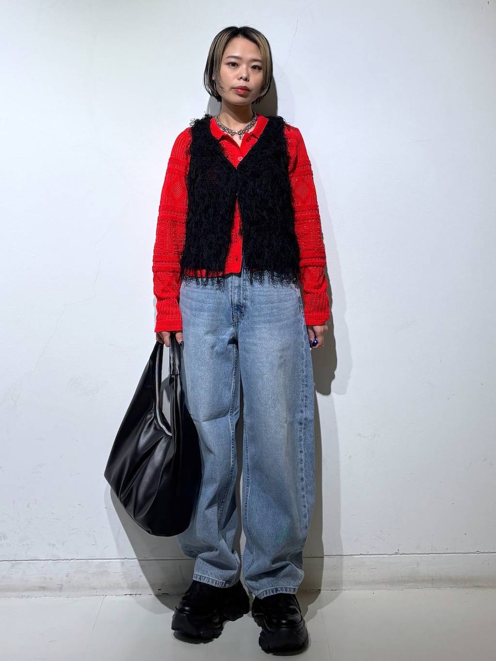 ブラック系のスニーカー、ブルー系のデニムパンツ、ブラック系のベストを着用したレディースの春コーディネートの2枚目の写真