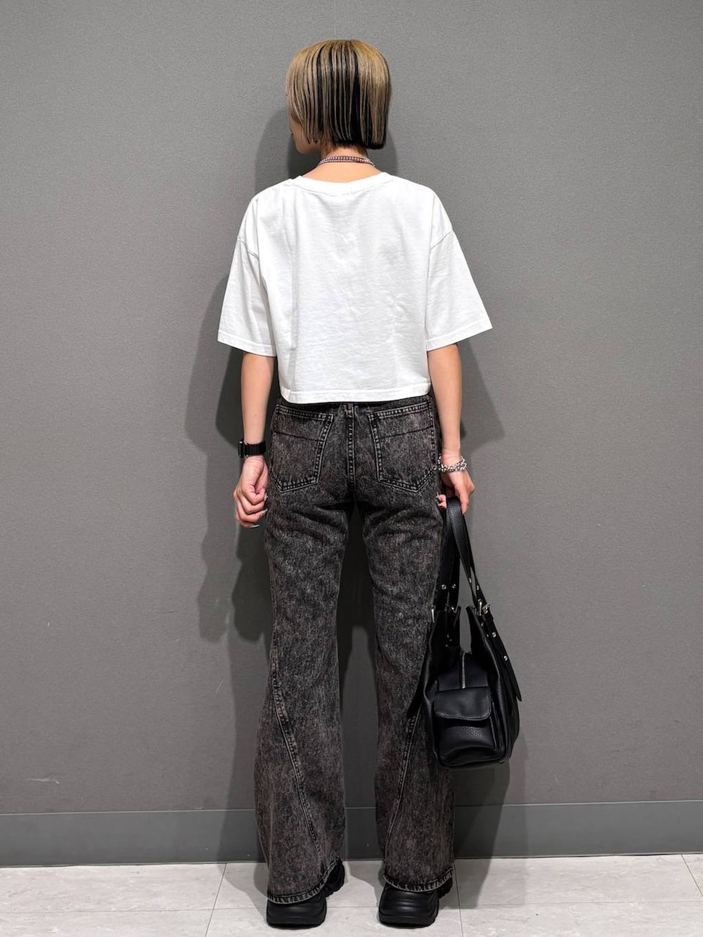 ブラック系のスニーカー、ブラック系のデニムパンツ、ホワイト系のTシャツ/カットソーを着用したレディースの春コーディネートの5枚目の写真