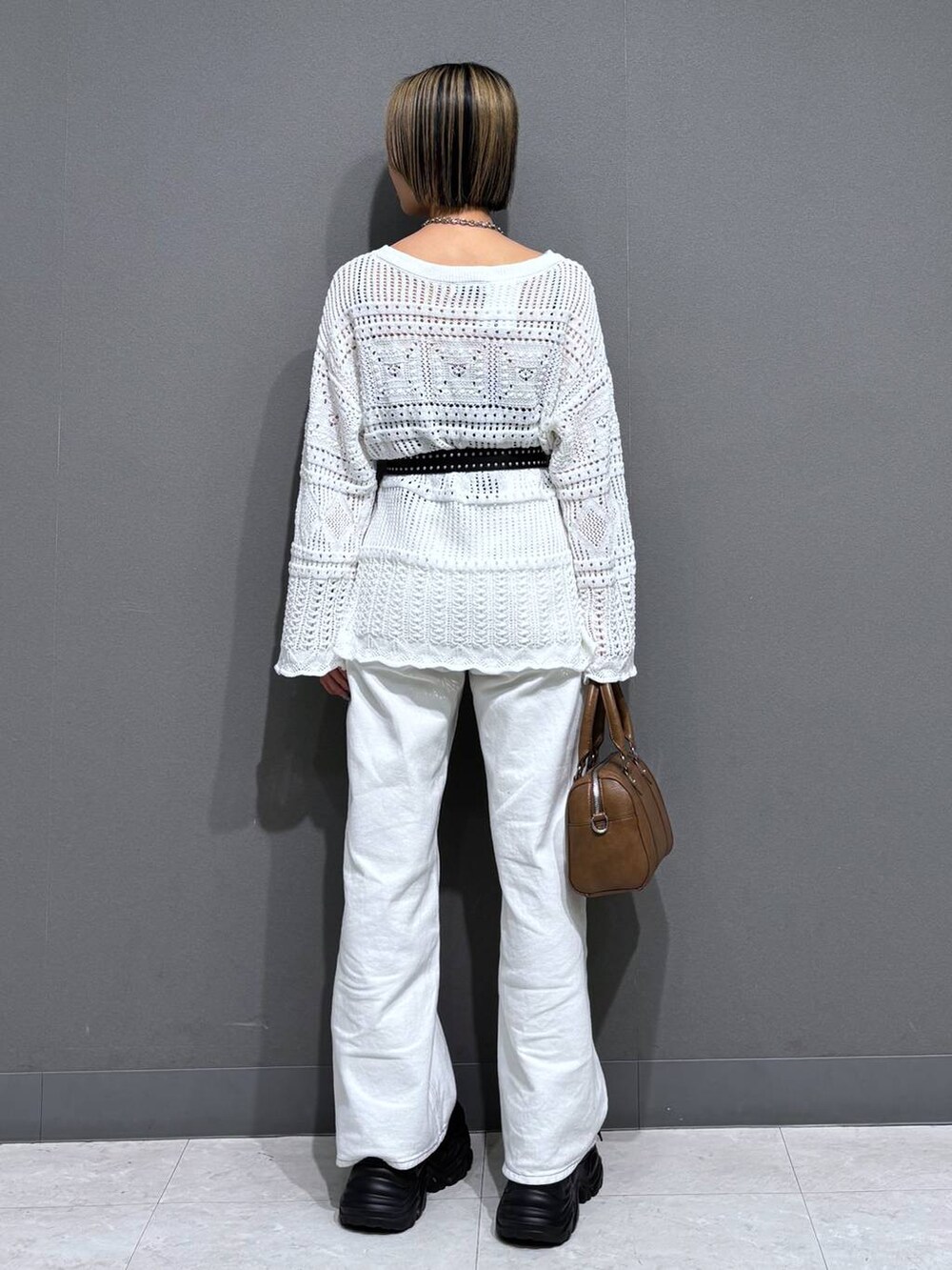 ブラック系のスニーカー、ホワイト系のスラックス、ブラウン系のボストンバッグを着用したレディースの春コーディネートの5枚目の写真