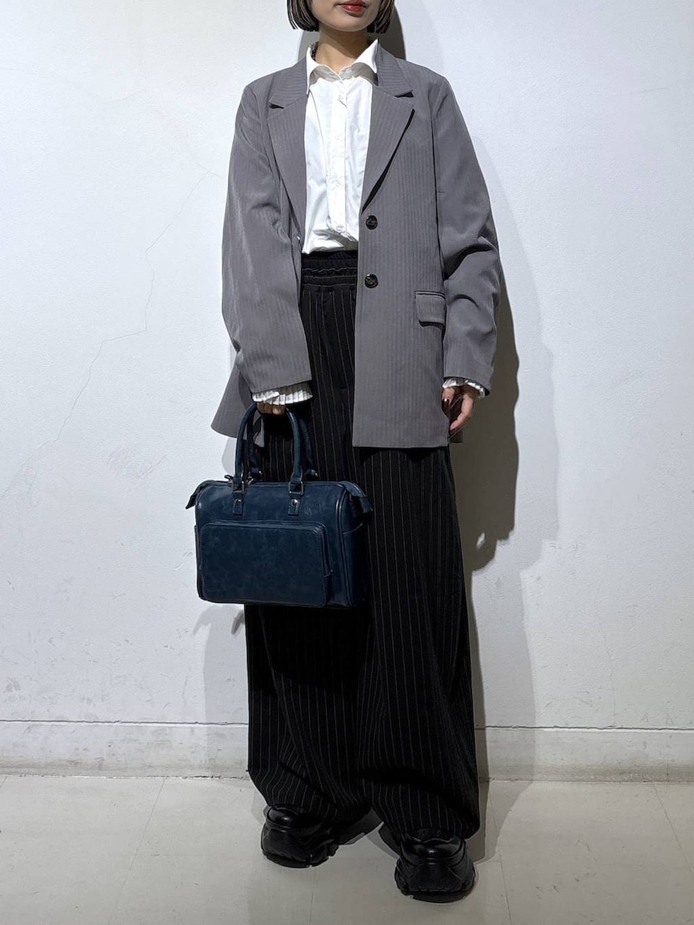 ブラック系のスニーカー、グレー系のテーラードジャケット、ブルー系のショルダーバッグを着用したレディースの冬コーディネートの2枚目の写真