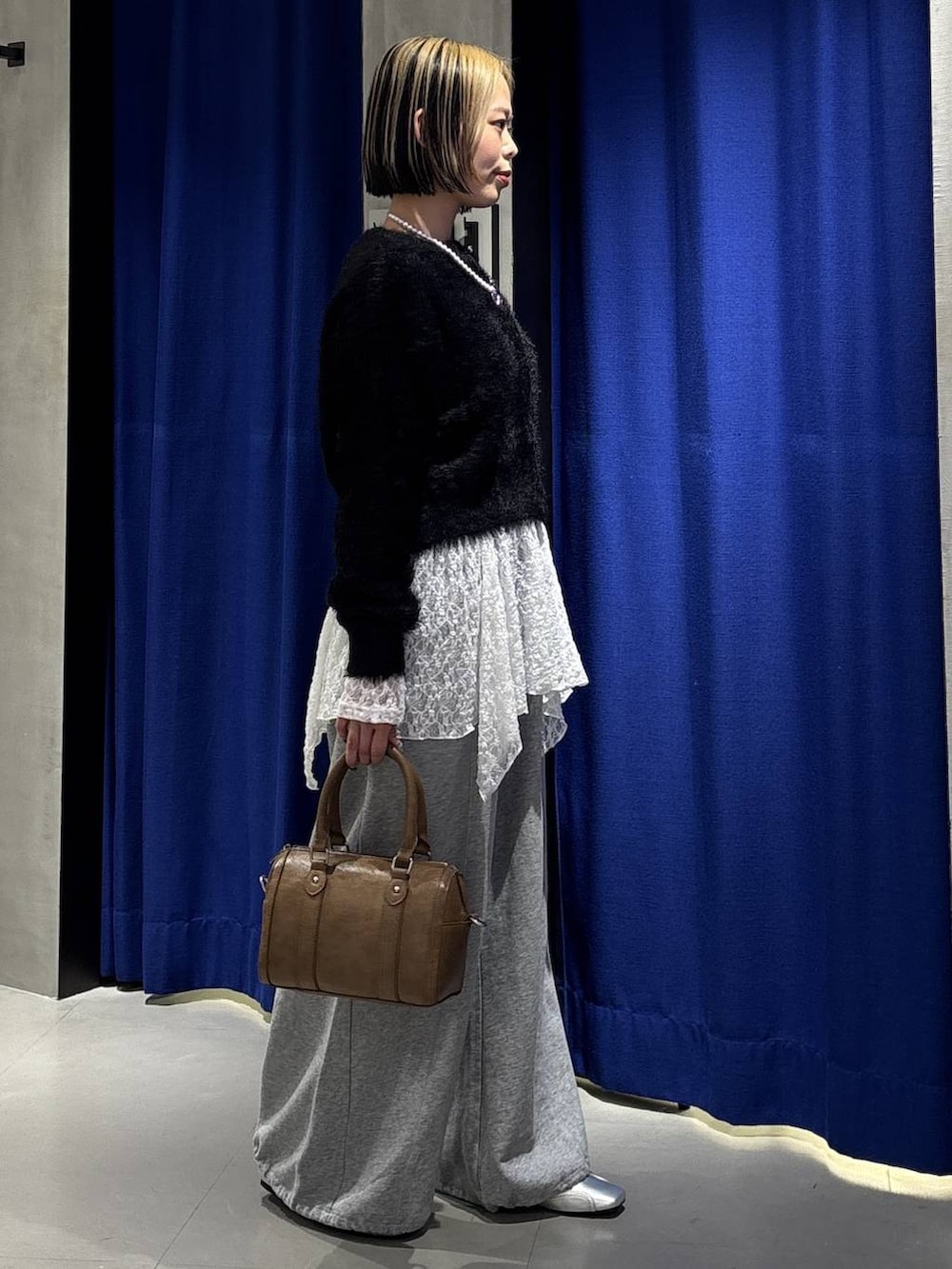 ブラウン系のボストンバッグ、グレー系のスウェットパンツ、シルバー系のスニーカーを着用したレディースの冬コーディネートの5枚目の写真