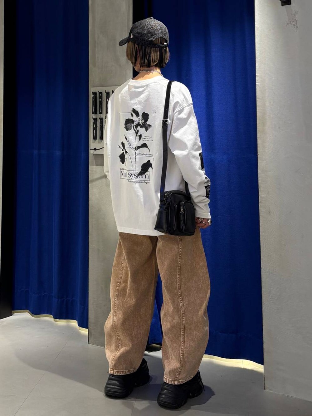ブラック系のスニーカー、ブラウン系のデニムパンツ、ブラック系のショルダーバッグを着用したレディースの春コーディネートの5枚目の写真